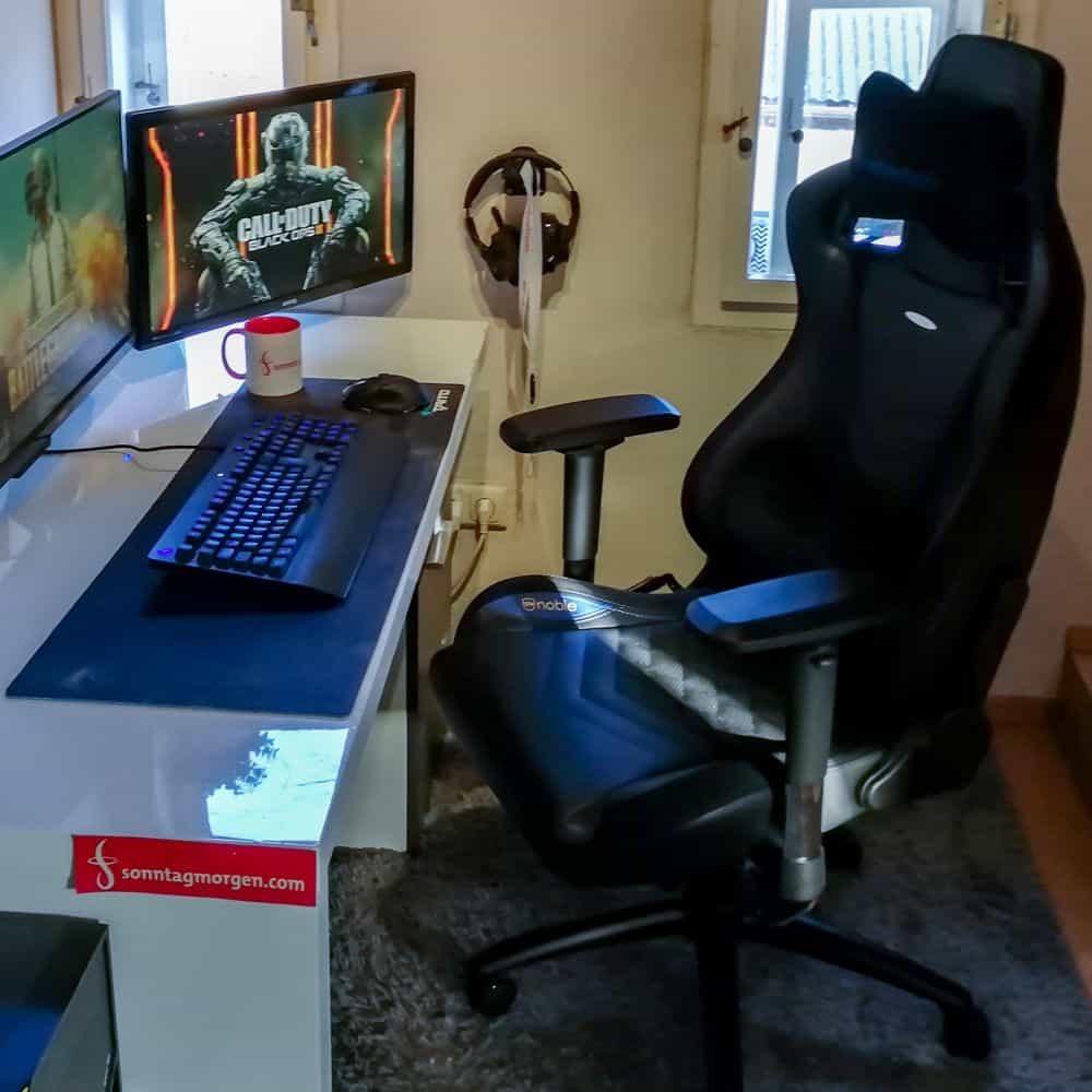 Gaming-Stuhl-Test – noblechairs EPIC rechts im Bild, auf der linken Seite Schreibtisch auf dem zwei Monitoren stehen